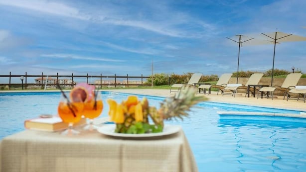 A poolside view with lounge chairs and a table with flowers.