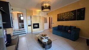 A spacious living room with a modern sofa, a glass coffee table, and a fireplace.