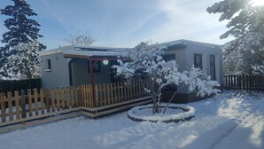 Ein kleines, eingeschossiges Gebäude mit Holzlattenzaun und einem schneebedeckten Garten.