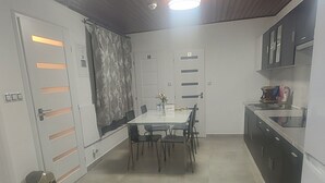Eine kleine Küche mit Esstisch, Schränken und Deckenventilator.