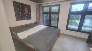 Ein Schlafzimmer mit einem Bett, einem großen Fenster und einem an der Wand hängenden Kunstwerk.