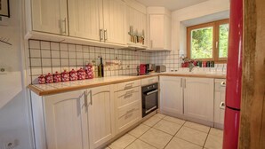 Une cuisine avec des meubles blancs, un dosseret carrelé et une fenêtre donnant sur un espace verdoyant.