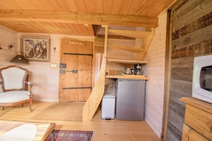 A compact cabin interior with a wooden interior, a small kitchenette, a sofa, and a dining table.