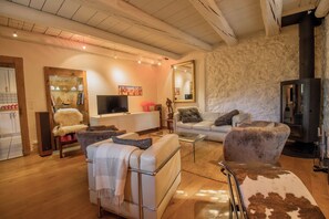 A modern living room with a fireplace, a television, and a stone wall.