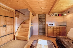 A wooden interior with a staircase, a microwave, and a small kitchenette.