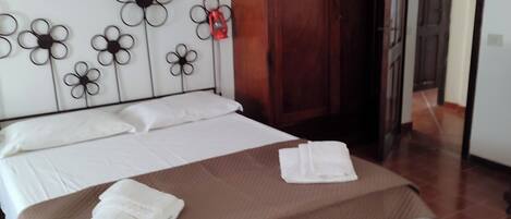 A hotel room with a bed, a wooden wardrobe, and a wall decoration of flowers.