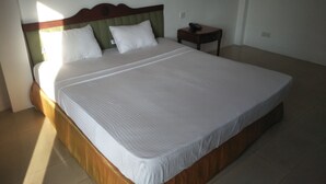 Ein großes Bett mit Holz Kopfteil und weißer Bettwäsche.