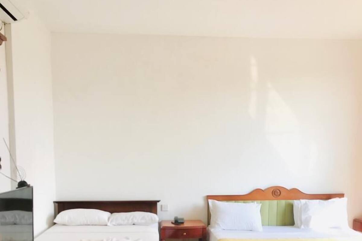 Ein Hotelzimmer mit zwei Betten, einem Fernseher und einem kleinen Tisch.