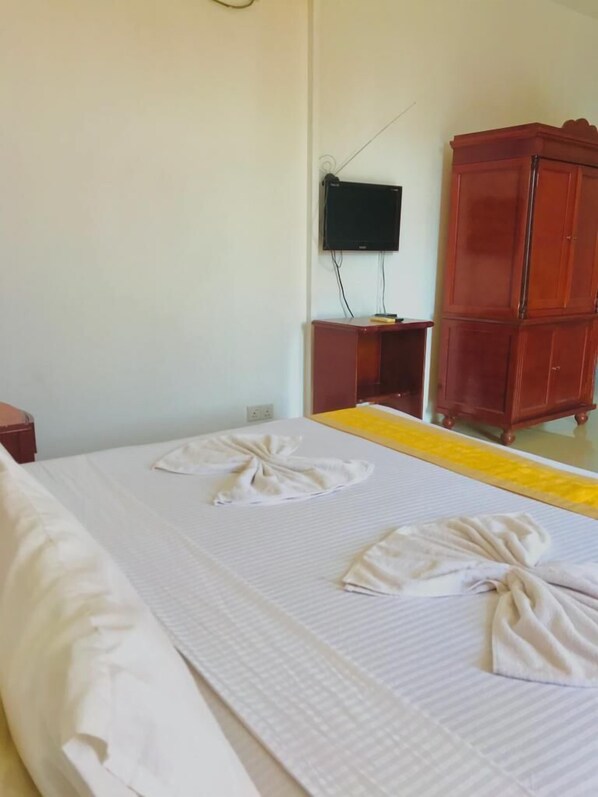 A hotel room with a bed, a television mounted on the wall, and a wooden wardrobe. - Airport Hotel Dream Paradise (Seeduwa - Katunayake)