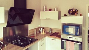 Una cocina moderna con extractor negro, armarios blancos, un microondas y una estufa.