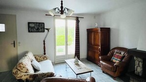 Una sala de estar con sofá, sillón de cuero, aparador de madera y chimenea.