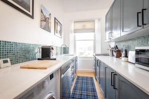 A modern kitchen with a built-in washing machine, a wooden cutting board, and a window with a view.