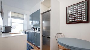 A modern kitchen with a large refrigerator, a dining table, and a window with a view.