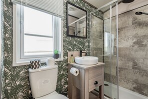A bathroom with a toilet, sink, and shower.