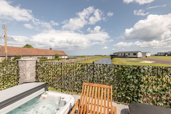 A hot tub, wooden chair, and a view of a golf course.