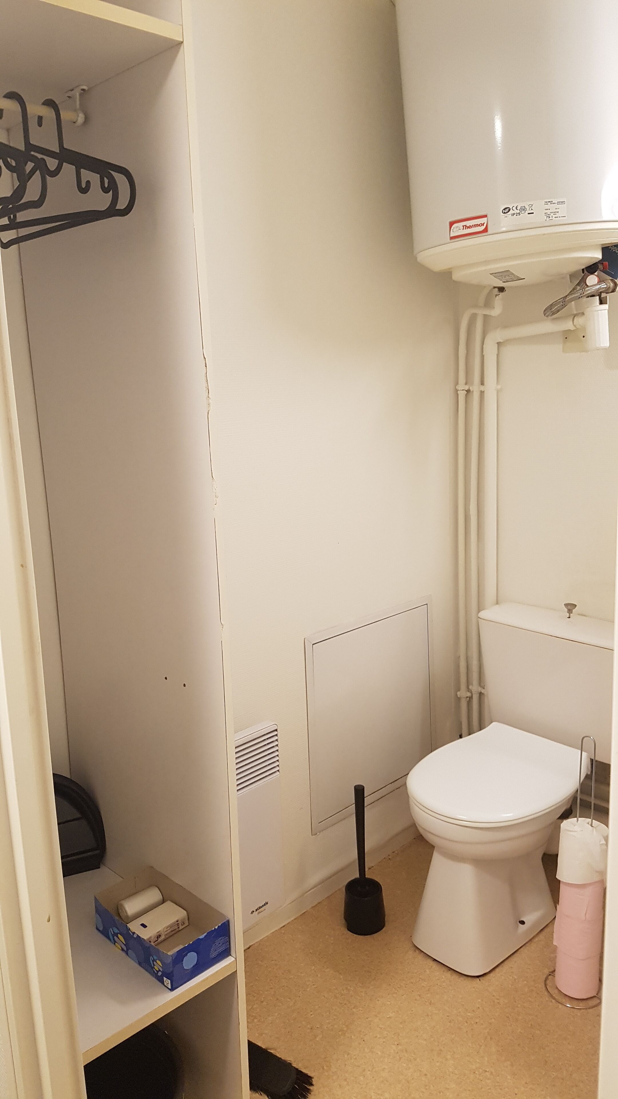 Un baño pequeño y funcional con inodoro, un lavamanos blanco y zona de ducha.