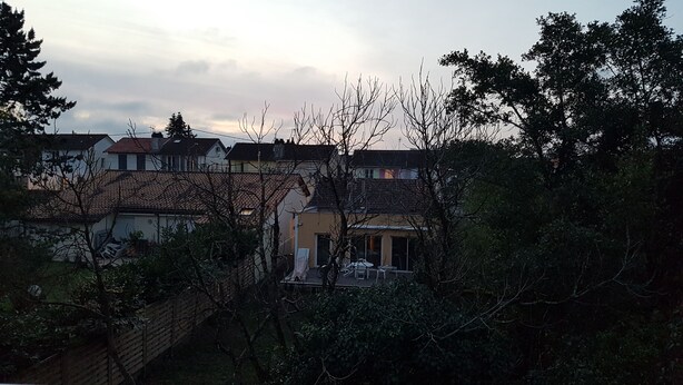 A residential area with houses, trees, and a clear sky.