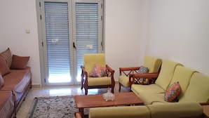 Un salon comprenant un canapé, des fauteuils, une table basse et un tapis à motifs.