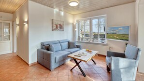 A modern living room with a grey sofa, a wooden coffee table, and a TV displaying a countryside scene. - 1 bedroom stunning apartment in Neukirchen (Neukirchen)