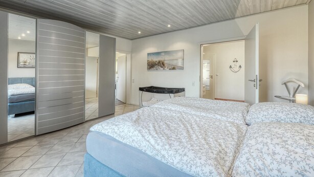 A modern bedroom with a large bed, a desk, and a sliding door leading to another room. - 1 bedroom stunning apartment in Neukirchen (Neukirchen)