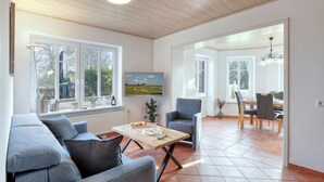 A modern living room with a sofa, a coffee table, and a TV. There is a dining area with a table and chairs. - 1 bedroom stunning apartment in Neukirchen (Neukirchen)