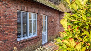 A brick building with a thatched roof, a window with a white frame, and a small porch area. - 1 bedroom stunning apartment in Neukirchen (Neukirchen)