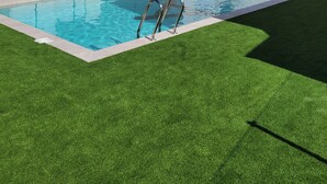 A modern two-story building with a swimming pool and artificial grass.