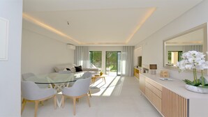 Uma sala de estar moderna com uma mesa de jantar de vidro, sofás brancos e um espelho grande.
