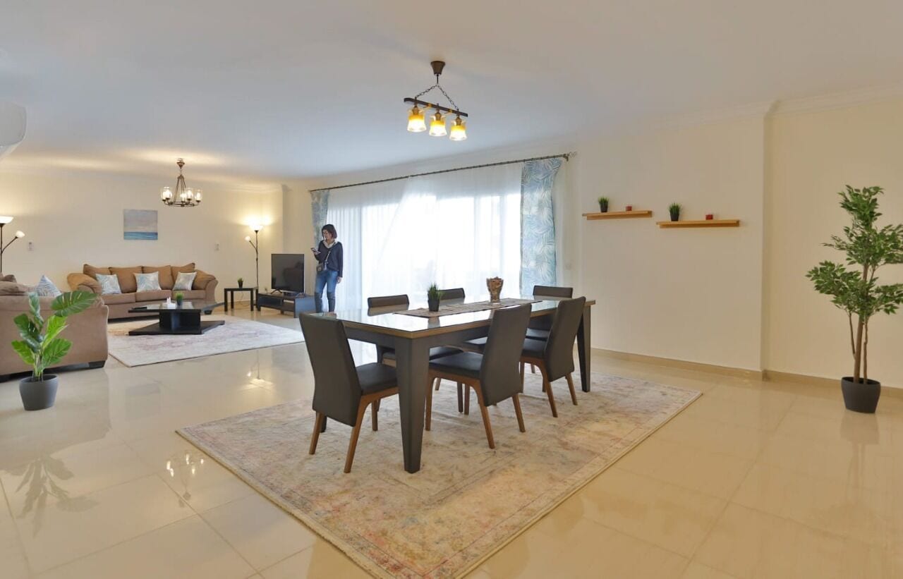 A spacious living room with a dining area, a sofa, a coffee table, and a TV.
