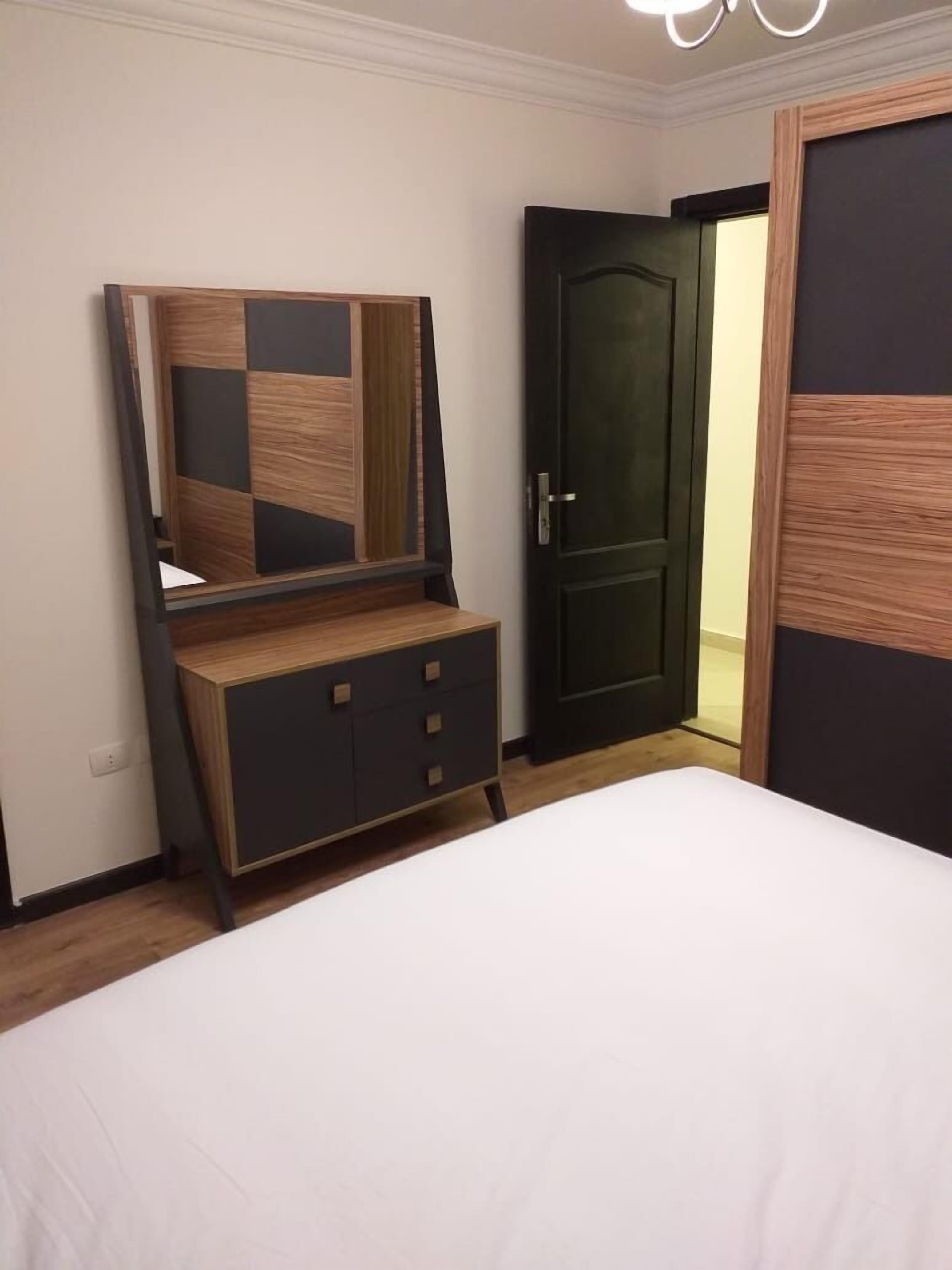 A bedroom with a bed, a dresser with a mirror, and a dark door.