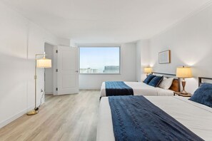 Una habitación de hotel con dos camas, un ventanal grande y una lámpara de pie.