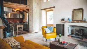 Una cocina moderna con electrodomésticos de acero inoxidable, un sillón amarillo y una chimenea.