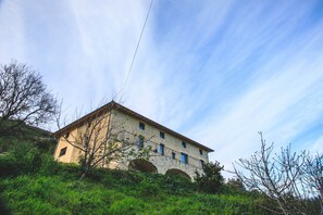 A stone building with a sloped roof, multiple windows, and arched doorways. - Chambre Avec vue mer Dans L'éco-lodge de Carbonaccio (Chiatra)