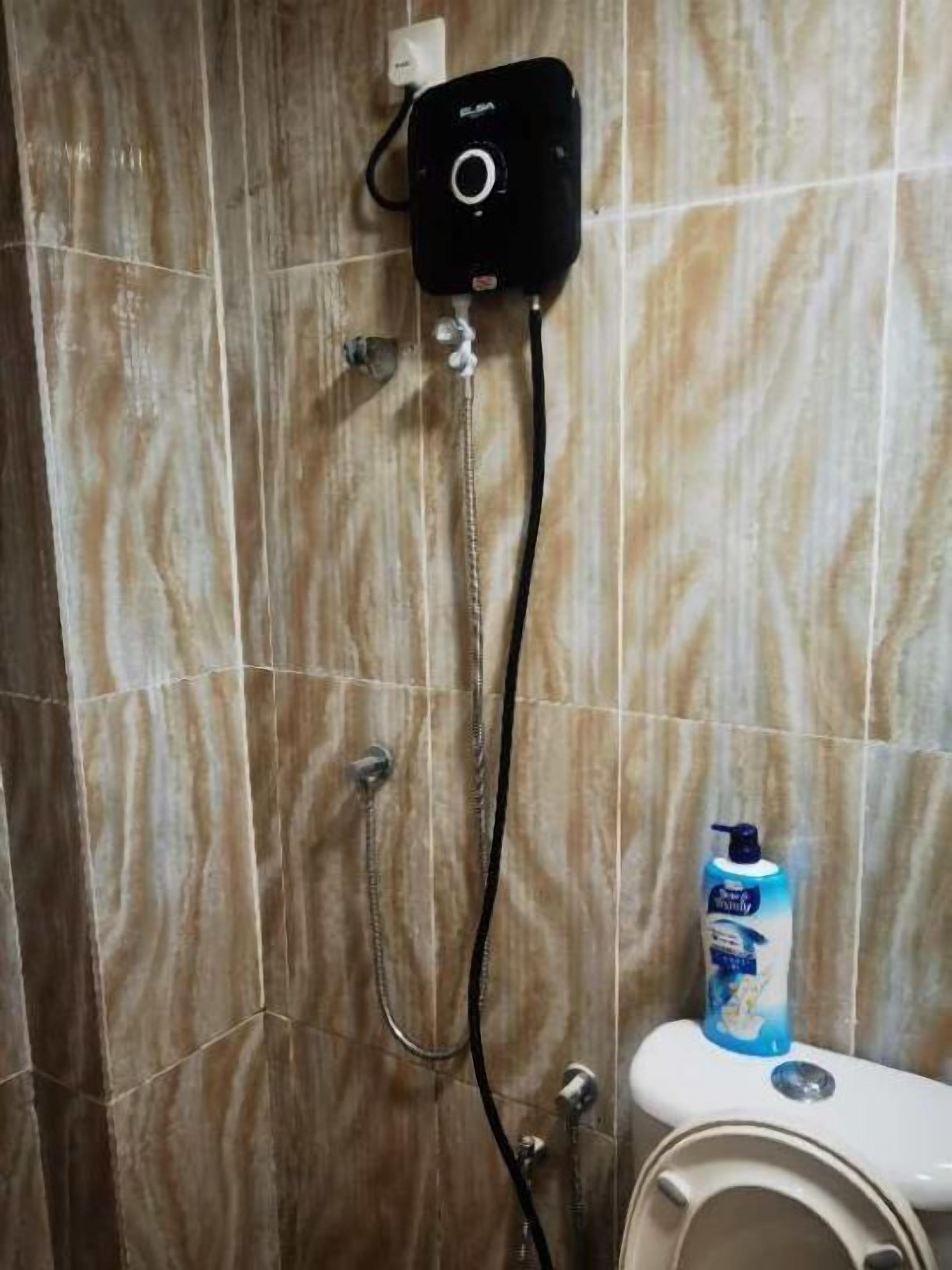 A bathroom with a shower, a toilet, and a bottle of hand soap on the counter.