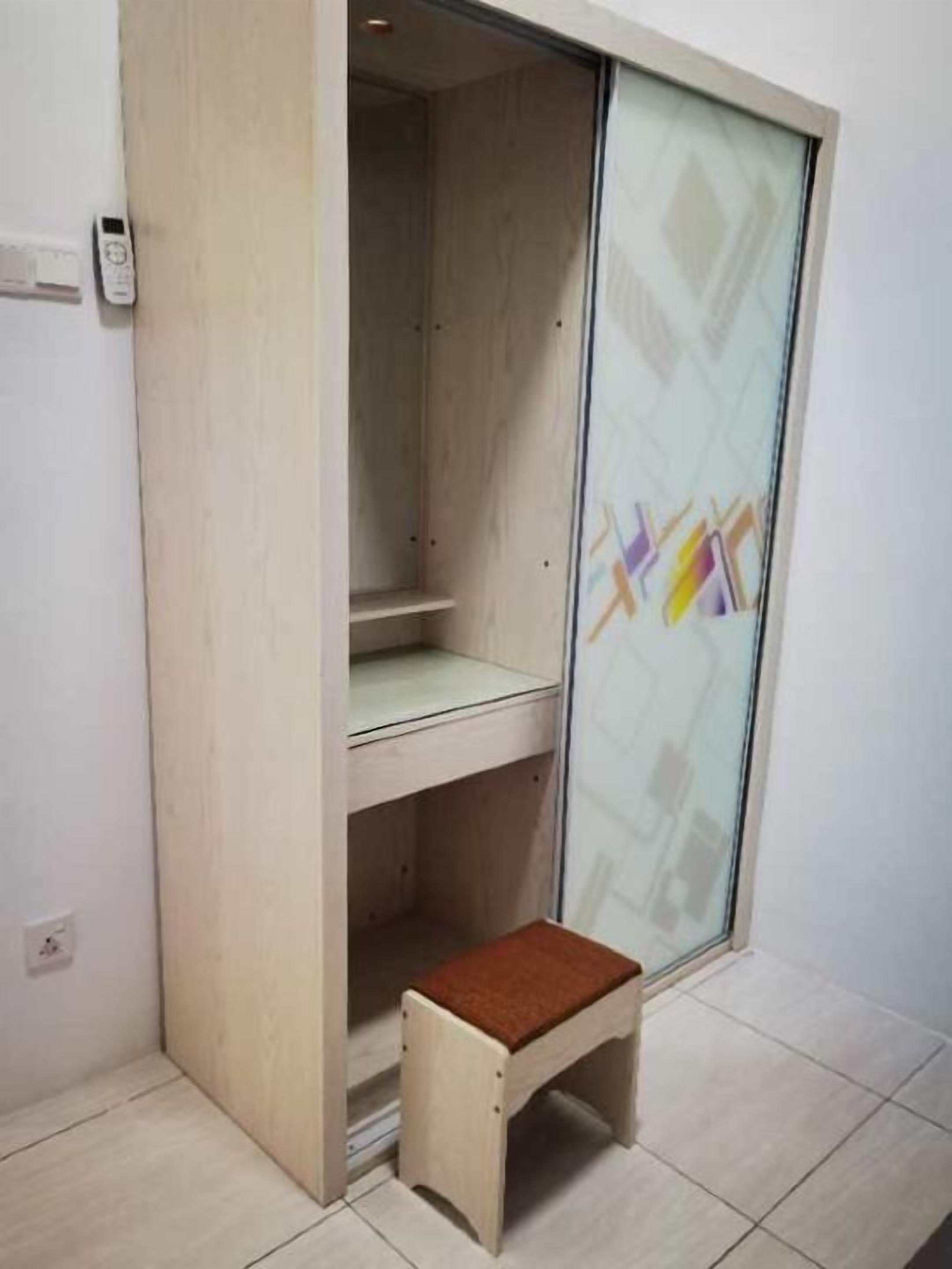 A small wooden bench with a brown cushion in a corner of a room with a sliding glass door.