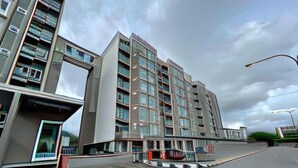 A modern multi-story building with a flat facade, large windows, and a flat roof.