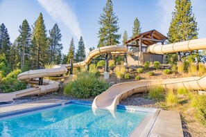 A pool area with multiple slides and a wooden structure.