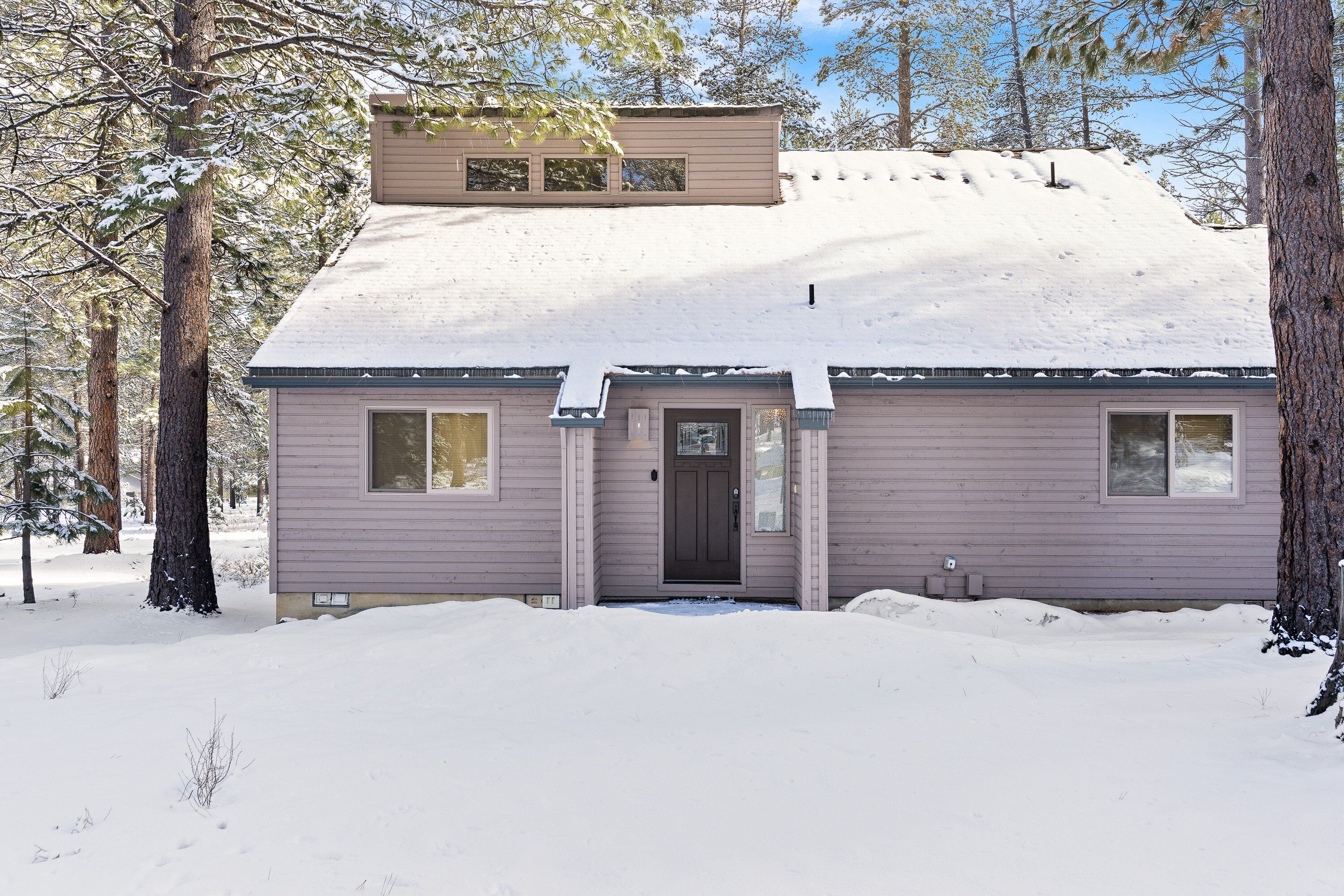 A two-story house with a snow-covered roof and a front door.