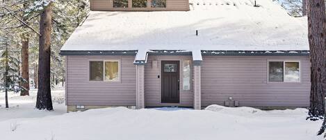 A two-story house with a snow-covered roof and a front door.