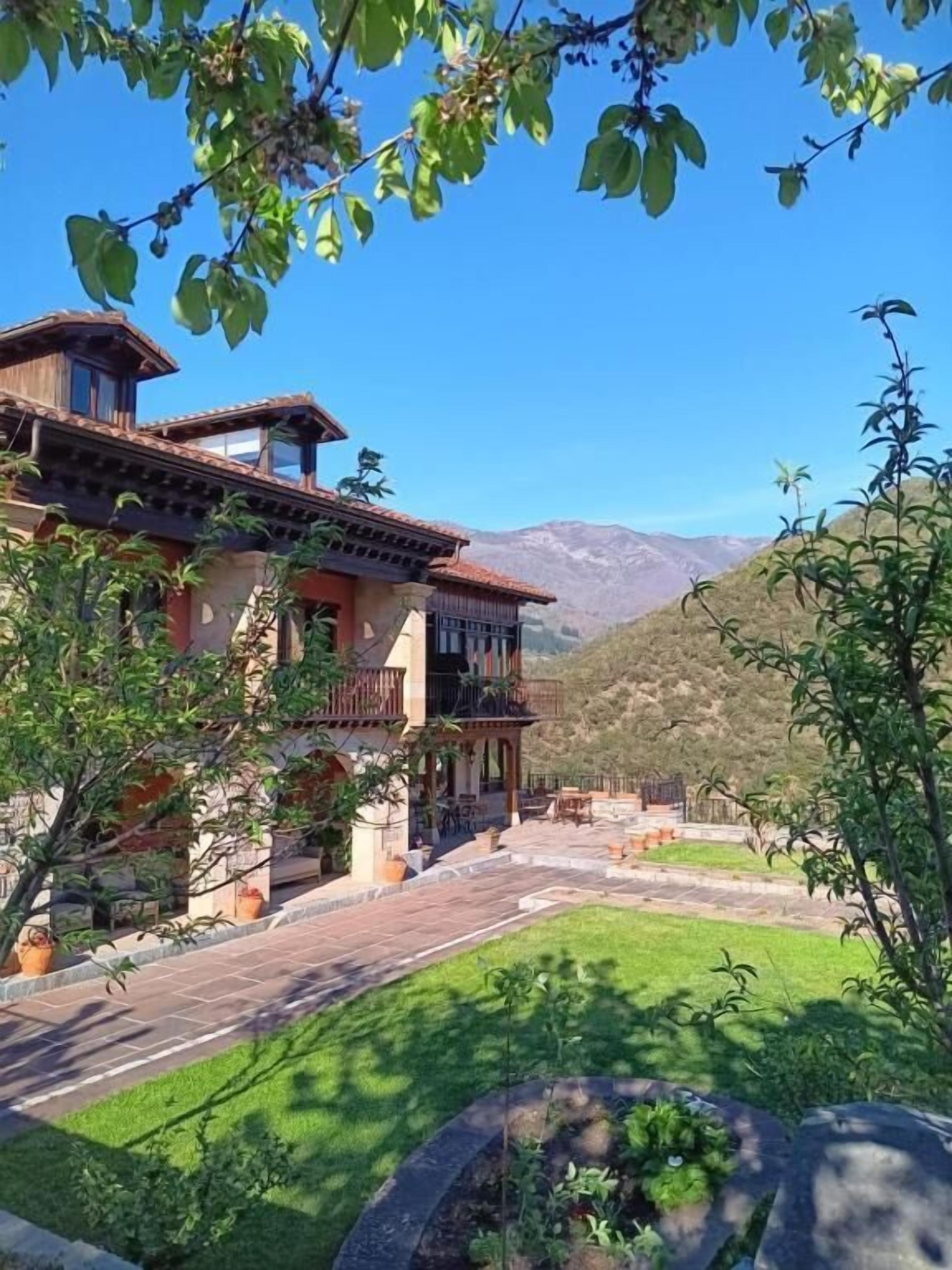 Una casa de dos pisos con balcón, entrada pavimentada y césped cuidado.