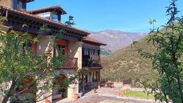 Una casa de dos pisos con balcón, entrada pavimentada y césped cuidado.