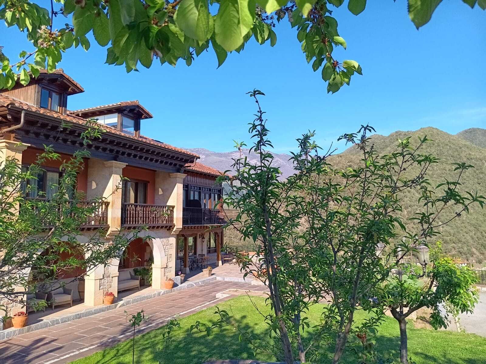 A two-story house with a balcony, a stone pathway, and a view of mountains.
