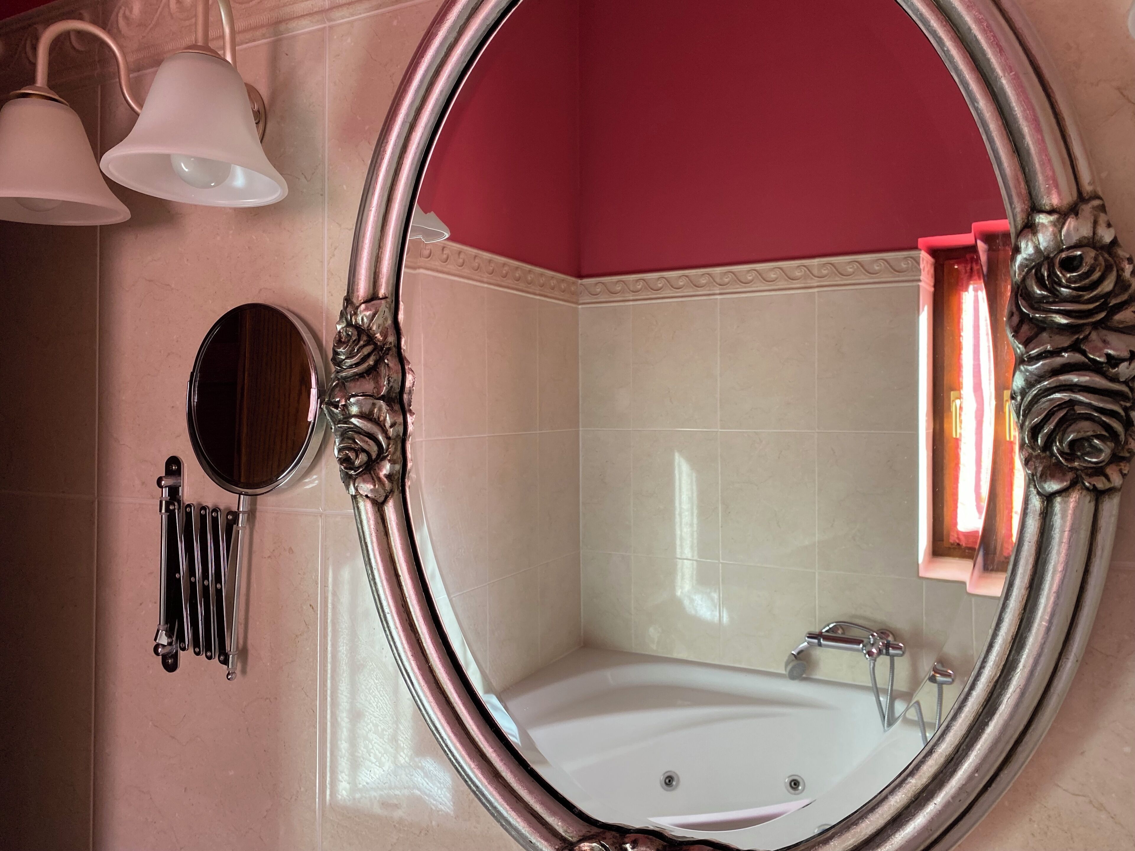 Ein Badezimmer mit einem großen, ovalen Spiegel, einer Badewanne und einem WC mit einem Handtrockner.