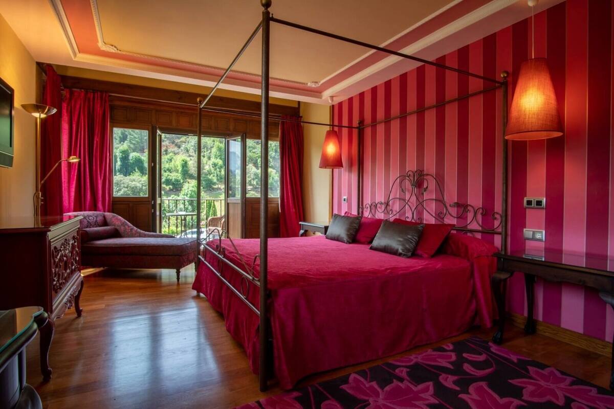 Un dormitorio con cama de dos plazas, un chaise lounge y vistas al exterior.