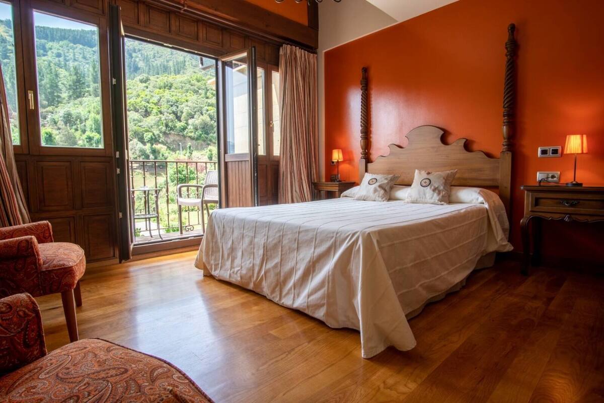 Un dormitorio con una cama grande, cabecera de madera y vistas a un balcón con barandilla de madera.