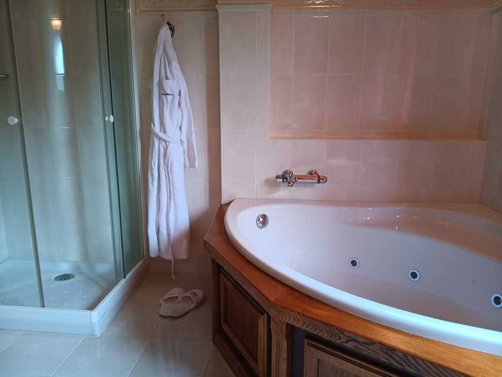 A bathroom with a glass shower enclosure, a white bathtub, and a wooden vanity.