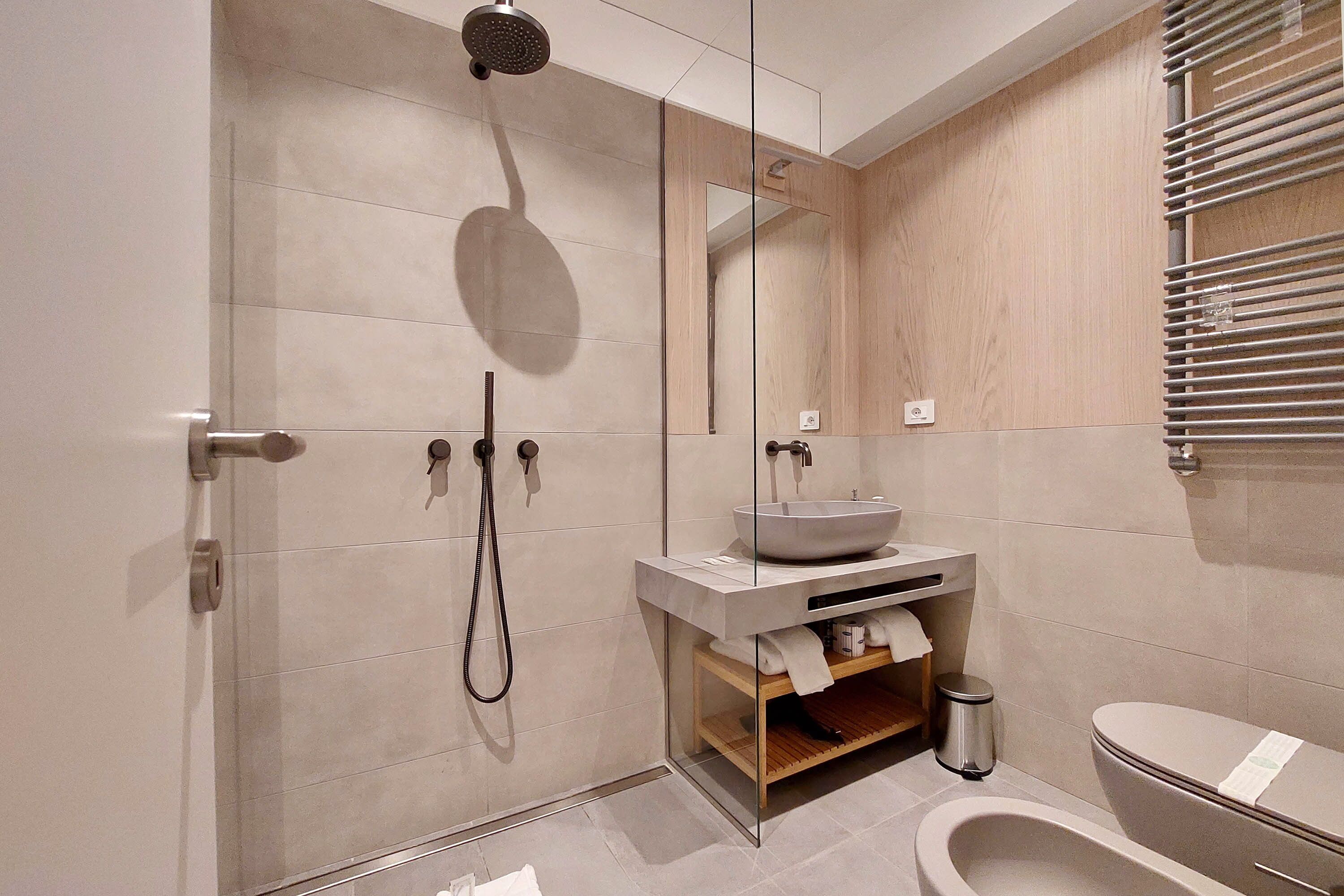 Une salle de bain moderne avec une douche à parois de verre, un lavabo sur colonne et des toilettes.