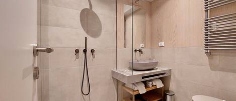Une salle de bain moderne avec une douche à parois de verre, un lavabo sur colonne et des toilettes.