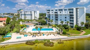 A modern hotel with a pool, multiple balconies, and a view of the marina. - Dolphin Point 305b 2 Bedroom Condo by RedAwning (Destin)