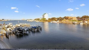 A marina with boats docked, a large white building with a green roof, and a clear blue sky. - Dolphin Point 305b 2 Bedroom Condo by RedAwning (Destin)